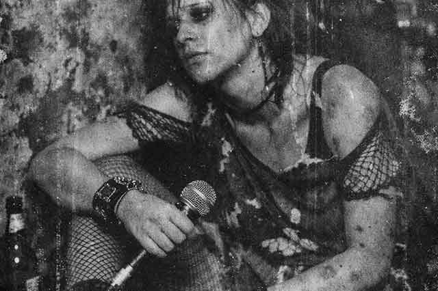 Fotografía estilo archivo antiguo de cantante punk femenina sentada en el suelo tras un concierto en Barcelona en 1982, con rayas, polvo y textura de negativo deteriorado